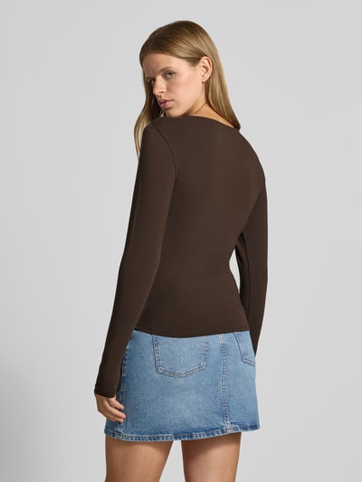 Frauenmodel trägt Regular Fit Langarmshirt aus Baumwoll-Mix Modell 'MIRA' von ONLY in Braun, kombiniert mit Jeansrock, Ganzkörperansicht Rückansicht, Damen Langarmshirt von ONLY.