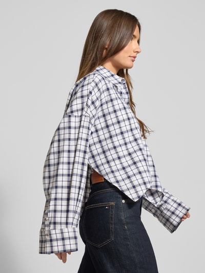 Frauenmodel trägt Oversized Hemdbluse mit Knopfleiste Modell 'OSHIA' von Drykorn aus reiner Baumwolle, kariertes Muster, Ganzkörperansicht Seitenansicht.