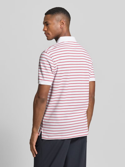 Männermodel trägt Regular Fit Poloshirt aus Baumwoll-Mix von Tommy Hilfiger, Optik: Allover-Muster mit Logo-Stitching, Ganzkörperansicht Rückansicht.