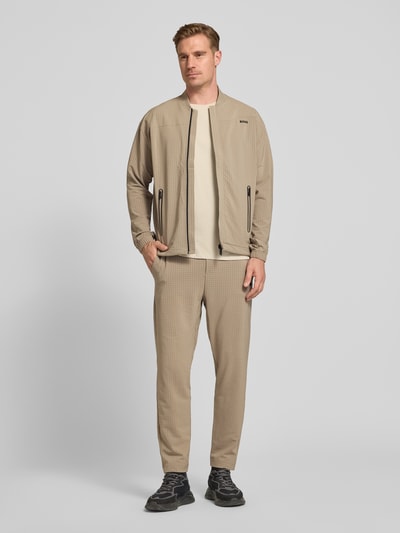 Männermodel trägt Tapered Fit Hose mit Waffelstrukturmuster Modell 'TERRACE' von BOSS Green, beige, Optik:Allover-Muster, Ganzkörperansicht von vorne.