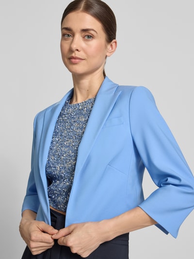 Frauenmodel trägt Cropped Blazer mit Reverskragen von Betty Barclay in Hellblau, offener Front, 3/4-Arm, elastischer Material-Mix, Nahaufnahme Oberkörper.