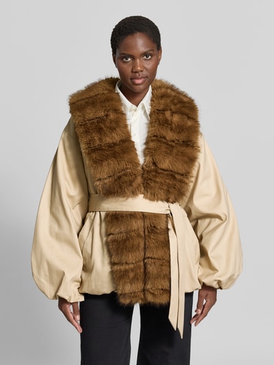 Frauenmodel trägt Jacke mit Kunstfellbesatz von ROTATE in Beige mit braunem Kunstfell, Material-Mix, taillierte Passform, Ganzkörperansicht von vorne.