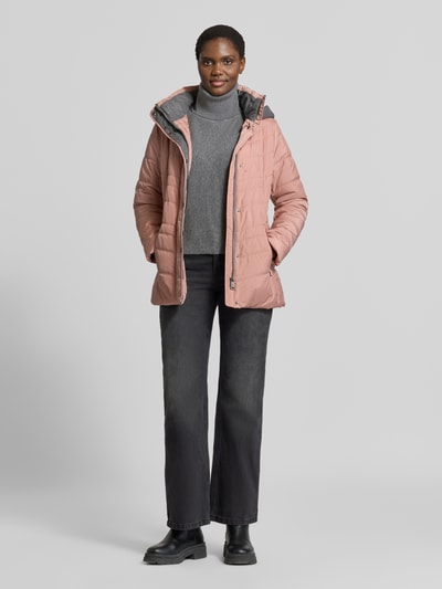 Kobiece model nosi kurtkę 'Jacke in Stepp-Optik mit Kapuze' od FUCHS SCHMITT, różowy kolor, z efektem pikowania, taliowany krój, kaptur, podszewka na stójce, wpuszczane kieszenie zapinane na zamek błyskawiczny, długość tyłu w rozmiarze 36: 74 cm, szerokość ramion w rozmiarze 36: 40 cm, szerokość klatki piersiowej w rozmiarze 36: 48 cm, długość rękawów w rozmiarze 36: 64 cm, widok całej sylwetki z przodu.