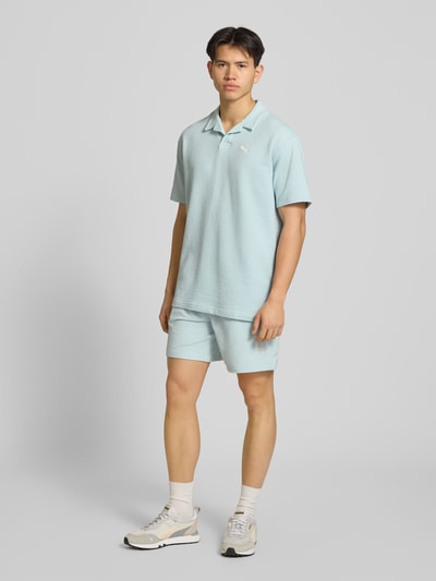 Männermodel trägt Shorts mit Logo-Stitching von PUMA PERFORMANCE in Hellblau mit Strukturmuster, geradem Schnitt, Ganzkörperansicht von vorne.