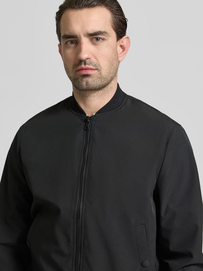 Mannelijk model draagt Regular Fit Bomberjacke mit Stehkragen van MCNEAL, zwart, elastische stofmix, rits, steekzakken, nahaufnahme bovenlichaam.