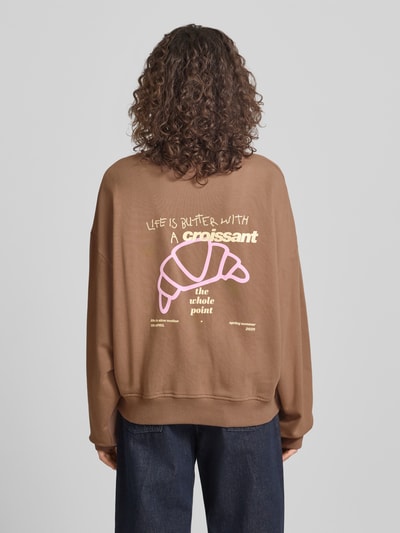 Frauenmodel trägt Regular Fit Sweater mit Logo-Stitching Modell 'Croissant' von OH APRIL aus brauner Baumwolle, Ganzkörperansicht Rückansicht.