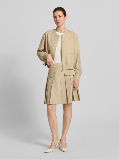 Frauenmodel trägt knielangen Faltenrock Modell 'Runi' von MOS MOSH aus Material-Mix mit Viskose-Anteil in Beige, A-Linie, Ganzkörperansicht von vorne. Bundweite bei Größe 36: 38 cm, Gesamtlänge bei Größe 36: 52 cm.