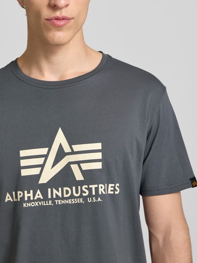 Männermodel trägt T-Shirt mit Logo und Rundhalsausschnitt von Alpha Industries aus Reine Baumwolle, Regular-Fit, Nahaufnahme Oberkörper.