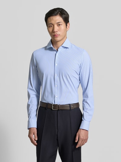 Männermodel trägt Slim Fit Business-Hemd mit Haifischkragen von SEIDENSTICKER im Allover-Look mit feinen blauen Streifen, Material-Mix mit Stretch-Anteil, Ganzkörperansicht von vorne