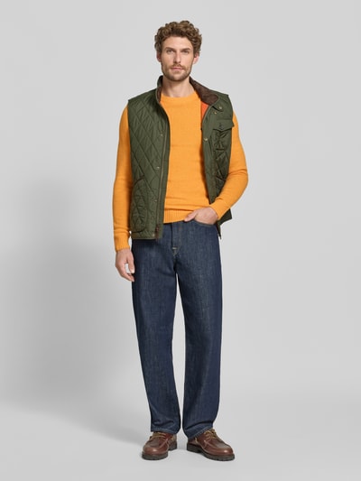Männermodel trägt Slim Fit Strickpullover aus reiner Wolle mit Label-Stitching von MCNEAL in Orange, Jeans, Ganzkörperansicht von vorne. Reine Wolle, gerippte Abschlüsse, Rückenlänge 66 cm, Ärmellänge 69 cm.