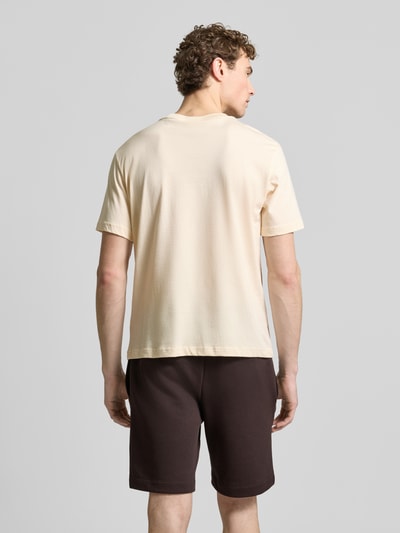 Männermodel trägt Regular Fit T-Shirt aus reiner Baumwolle von Lacoste in Two Tone Optik mit Label Patch, Rückansicht, Ganzkörperansicht.