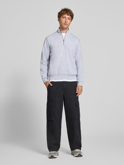 Männermodel trägt Regular Fit Sweatshirt mit Baumwoll-Anteil Modell 'Bradley' von JACK & JONES in Hellgrau, Ganzkörperansicht von vorne, Herren Sweatshirt, Troyer-Kragen, Material-Mix, Rückenlänge 68 cm, Ärmellänge 66 cm.
