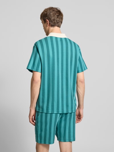 Männermodel trägt Relaxed Fit Poloshirt mit Label-Stitching Modell 'CLASS' von PUMA im Baumwoll-Mix mit Streifenmuster, Ganzkörperansicht Rückansicht.