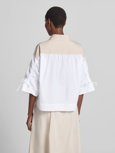 Frauenmodel trägt Boxy Fit Bluse mit 3/4-Arm von Marc Cain aus reiner Baumwolle, Hemdblusenkragen, Knopfleiste, zweifarbig, Ganzkörperansicht Rückansicht.