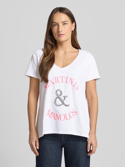 Frauenmodel trägt Relaxed Fit T-Shirt mit Pailettenbesatz Modell 'Martinis Manolos' von miss goodlife, weiß, V-Ausschnitt, Statement-Print, Ganzkörperansicht von vorne.