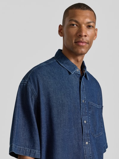 Męski model nosi Oversized Jeanshemd aus Baumwoll-Lyocell-Mix od Armedangels, denim, twill, kieszonka na piersi, zbliżenie na górną część ciała