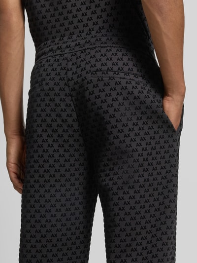 Männermodel trägt Sweatpants im Allover-Look mit Logo-Muster Modell 'PANTALONI' von Armani Exchange, Nahaufnahme Rückansicht. Baumwoll-Mix mit Stretch-Anteil, elastischer Bund und Tunnelzug, Regular Fit, schwarze und graue Töne, strukturierte Oberfläche.