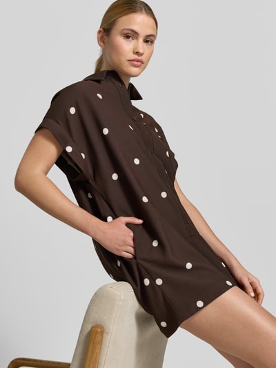Frauenmodel trägt Lockeren Jumpsuit mit Knopfdetail - curated by Mary Braun von Style Icon Collection, Braun mit weißen Punkten, Relaxed-Fit, Allover-Look, Hemdblusenkragen, Knopfleiste, Brustweite 60 cm, Rückenlänge 65 cm, Ärmellänge 14 cm, Gesamtlänge 84 cm, Innenbeinlänge 5 cm, Ganzkörperansicht von vorne.