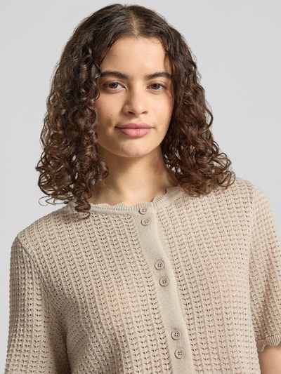 Frauenmodel trägt Regular Fit Strickjacke aus reiner Baumwolle Modell 'SCOUT' von PIECES für Damen, beige mit Knopfleiste, Nahaufnahme Oberkörper.