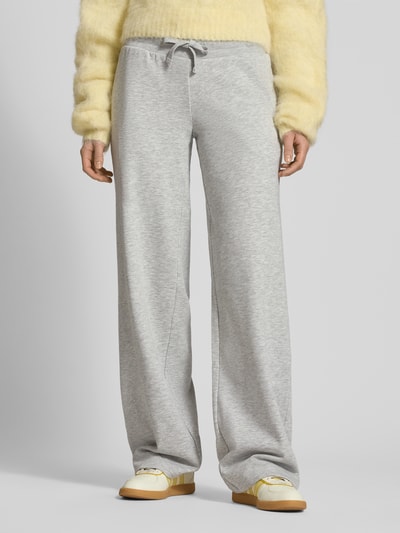 Kobiece modelka nosi Wide Fit Sweatpants mit Viskose-Anteil od REVIEW, mieszanka bawełny i wiskozy, krój wide fit, elastyczny pas, tunel, długość wewnętrzna nogawki w rozmiarze S: 89 cm, kolor jasnoszary, gładka faktura, widok całej sylwetki z przodu.