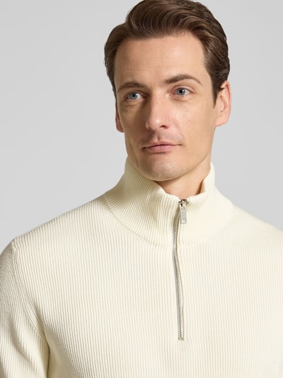 Männermodel trägt Strickpullover mit Stehkragen und Reißverschluss von Lindbergh in Ripp-Optik, cremefarben, Nahaufnahme Oberkörper.