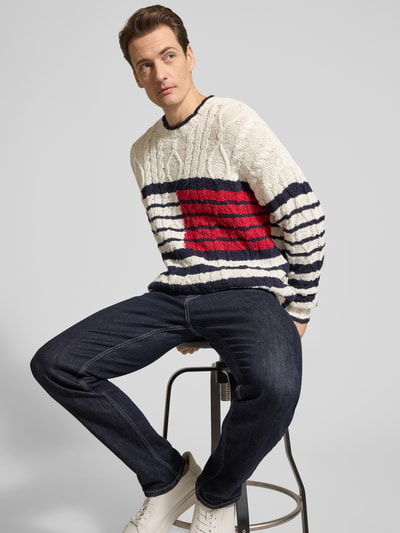 Männermodel trägt Relaxed Fit Strickpullover aus reiner Baumwolle von Tommy Hilfiger, Optik: Unifarben, Strickoptik, Logo-Detail, Rundhals, Langarm, gerippte Abschlüsse, Materialverarbeitung: Strick, Ganzkörperansicht von vorne.