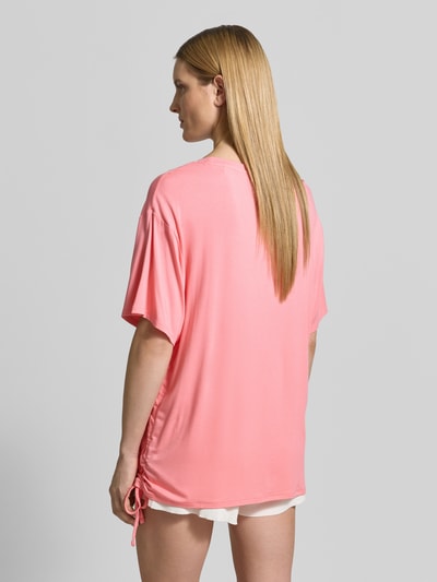 Modelka nosi damski t-shirt z mieszanki wiskozy, luźny krój, nadruk z logo, tunel, model 'COULISSE' od Guess, widok z tyłu całej sylwetki.