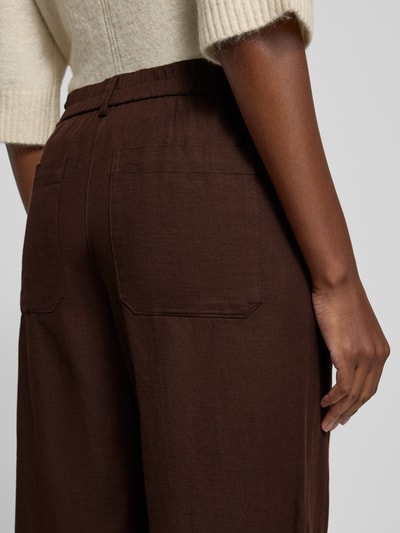 Frauenmodel trägt OPUS Culotte mit Eingrifftaschen Modell 'Meeri breath' aus braunem Baumwoll-Leinen-Mix, Nahaufnahme Rückansicht.