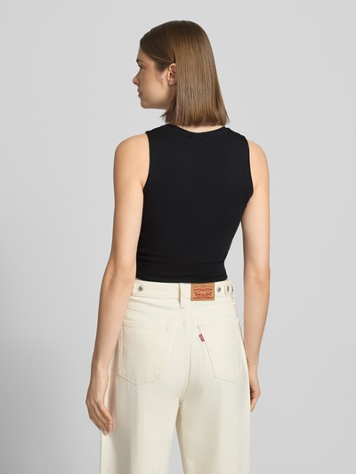 Vrouwenmodel draagt Crop Top met Knotendetail model 'TWIGGI' van Noisy May, katoenmix met stretch, kort, ronde hals, ruglengte maat S 37 cm, Ganzkörperansicht Rückansicht.