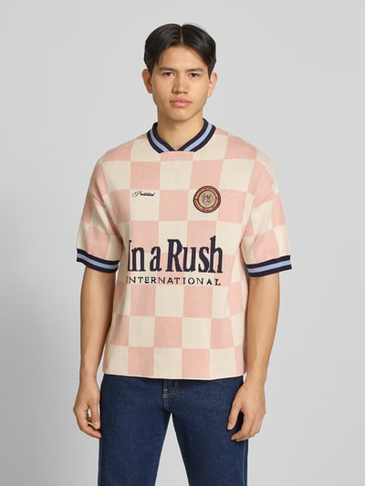 Männermodel trägt Strickshirt mit Label-Stitching Modell 'Victory' von PROHIBITED in Creme und Rosa, Relaxed-Fit, Reine Baumwolle, Ganzkörperansicht von vorne.