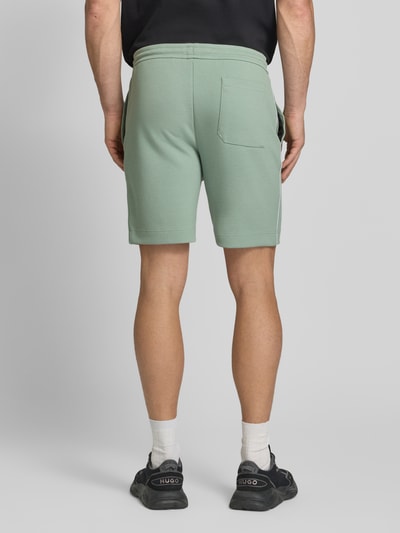 Männermodel trägt Regular Fit Sweatshorts aus Baumwoll-Mix Modell 'JT_JOIN HEADLO' von BOSS Green, mintgrün, Ganzkörperansicht Rückansicht.