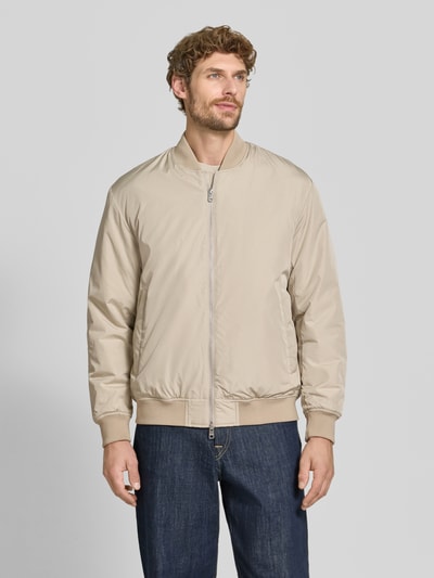 Männermodel trägt Regular Fit Bomberjacke mit Baseball-Kragen Modell 'CHARLES' von Selected in Beige, glatte Textur, Ganzkörperansicht von vorne. Herren Bomberjacke.