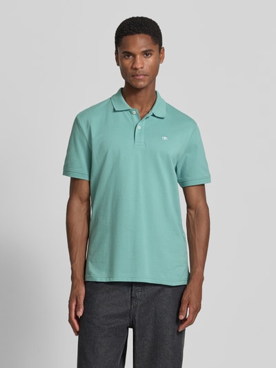Männermodel trägt Regular Fit Poloshirt aus reiner Baumwolle von Tom Tailor in Mintgrün, glatte Struktur, Ganzkörperansicht von vorne.