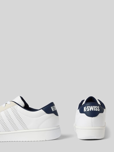 Produktfoto, Sneaker mit Label-Print Modell 'COURT' von K-Swiss in Weiß und Dunkelblau, abgerundete Form, Lochmuster, strukturierte Sohle, Label-Print an der Ferse, Kontext: Herren Sneaker, Schnürverschluss, Absatzhöhe 3 cm, Schafthöhe 7 cm, Schaftweite 10 cm