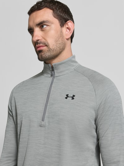 Männermodel trägt Funktionsshirt mit Logo und Reißverschluss von Under Armour in Grau, Stehkragen, Regular Fit, Nahaufnahme Oberkörper.