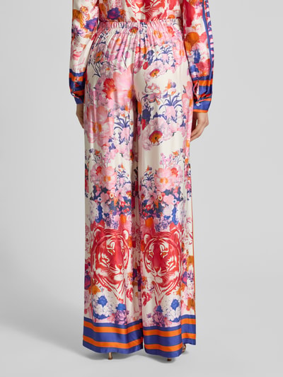 Frauenmodel trägt Wide Leg Hose aus Viskose Modell 'wild Flower' von miss goodlife, bunter Blumen- und Tigerprint, glänzende Textur, Ganzkörperansicht Rückansicht. Damenhose mit Knopfverschluss, Teilungsnähten, Bundweite 35 cm, Innenbeinlänge 88 cm bei Größe S.