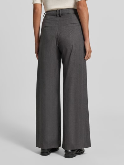 Kobieta modelka nosi spodnie Wide Leg Hose mit Bundfalten Modell 'JAYCE' od SUNCOO PARIS z mieszanki materiałów z lnem, kolor szary, zakładki w pasie, kieszenie z tyłu, szerokość w rozmiarze S 36 cm, długość wewnętrzna nogawki 79 cm, widok całej sylwetki od tyłu.