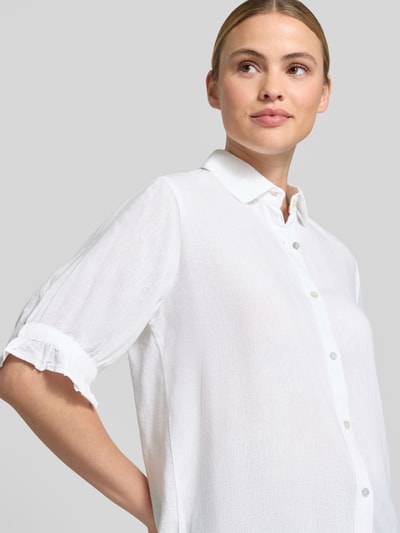 Kobiece model prezentuje bluzka z mieszanki wiskozy i lnu 'Bluse mit Leinen-Anteil und Rüschensaum' od Christian Berg Woman, biały kolor, kołnierzyk koszulowy, listwa guzikowa, rękawy z falbanami, krój regular fit, długość tyłu w rozmiarze 36: 68 cm, długość rękawów w rozmiarze 36: 30 cm; zbliżenie na górną część ciała z przodu.