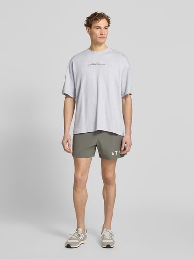 Männermodel trägt T-Shirt mit Label-Print und Rundhalsausschnitt von HALO, reine Baumwolle, Boxy Fit, grau, Ganzkörperansicht von vorne.