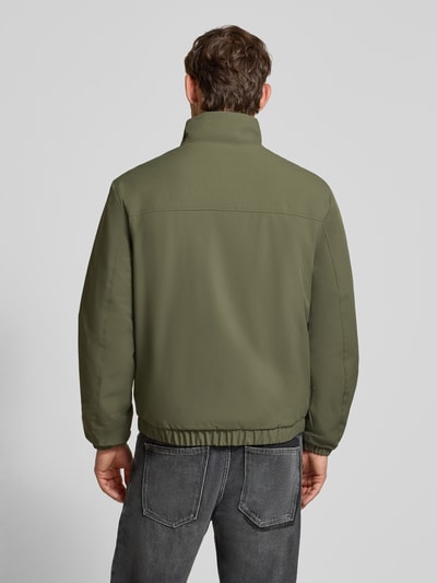 Männermodel trägt Relaxed Fit Blouson mit Stehkragen von Tom Tailor Denim in Olivgrün, elastischer Saum, Herren Bomberjacke, Ganzkörperansicht Rückansicht.