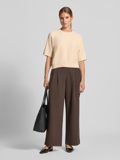 Frauenmodel trägt Relaxed Fit Pullover aus Viskose-Mix Modell 'Thamira' von MSCH Copenhagen in Beige, Strick-Optik, 1/2-Arm, Frontansicht, Ganzkörperansicht von vorne.