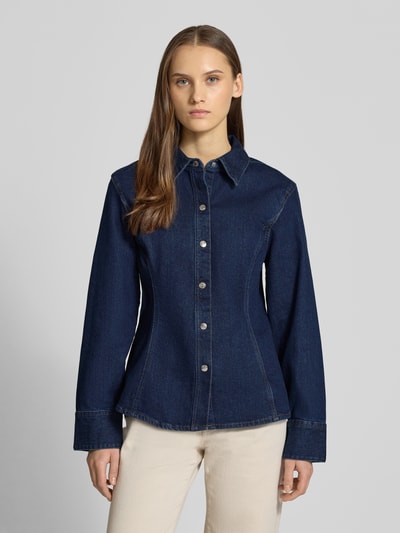 Frauenmodel trägt Regular Fit Jeansbluse Modell 'Classic' von Calvin Klein Jeans im dunklen Denim-Optik, Ganzkörperansicht von vorne, aus elastischem Baumwoll-Mix, langärmelig, taillierte Passform, Hemdblusenkragen, durchgängige Knopfleiste und Sportmanschetten, Rückenlänge 65 cm, Ärmellänge 60 cm bei Größe S.