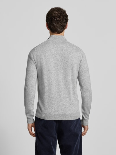 Männermodel trägt hellgrauen Pullover aus reiner Wolle von GANT mit Feinstrick und langem Arm, Ganzkörperansicht Rückansicht.