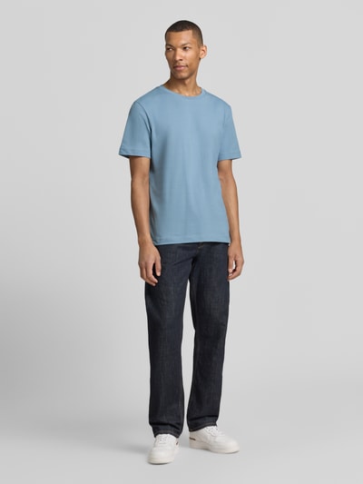 Męski model nosi Regular Fit T-Shirt aus Baumwoll-Mix von Tom Tailor, kolor jednolity, krój regular fit, okrągły dekolt, krótki rękaw, faktura piqué, materiał bawełniany, pełna sylwetka z przodu.