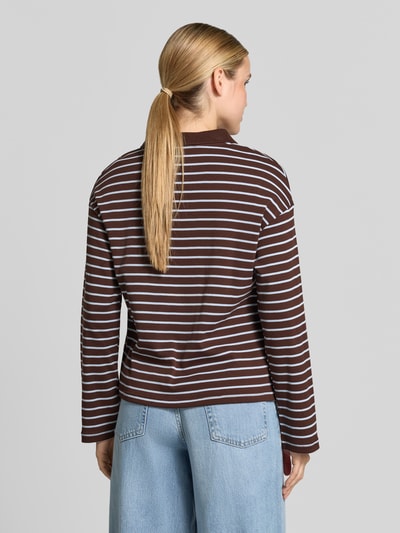 Frauenmodel trägt Relaxed Fit Poloshirt aus reiner Baumwolle Modell 'TIMOTHEE' von MANGO, braun-weiß gestreift, Langarm, Rückenansicht.