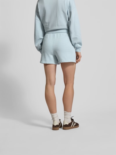 Frauenmodel trägt Regular Fit Shorts mit Logo-Stitching von Anine Bing aus reiner Baumwolle in Hellblau, elastischer Bund, Eingrifftaschen, Ganzkörperansicht Rückansicht.
