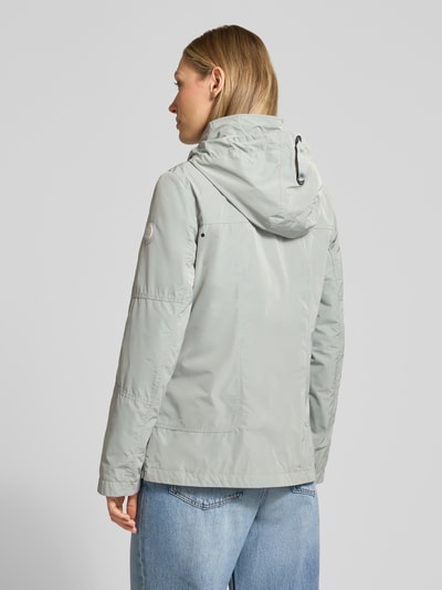Frauenmodel trägt Weather Protection Jack mit Reißverschlusstaschen von Gil Bret in Hellgrau, Kapuze, Stehkragen, Rückansicht, Ganzkörperansicht Rückansicht. Regular Fit, glatte Textur, Länge bis Hüfte, sichtbare Nähte, Reißverschlüsse, Damenjacke Kontext integriert.