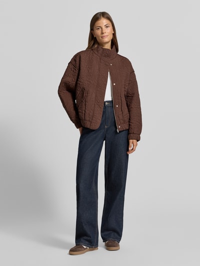 Frauenmodel trägt Blouson mit Ziernähten Modell 'FIPURA' von YAS, braun mit floralen Stickereien, lockere Passform, Ganzkörperansicht von vorne.