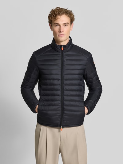 Männermodel trägt zwarte gewatteerd jack met opstaande kraag, tweewegritssluiting, ritszakken, Model 'ALEXANDER' van Save The Duck, slim fit, Heren, ruglengte maat M 67 cm, schouderbreedte 47 cm, borstwijdte 57 cm, mouwlengte 68 cm, geheel van voren
