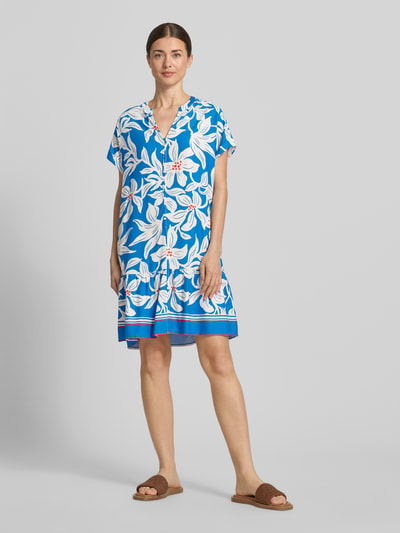 Frauenmodel trägt Knielanges Kleid aus Viskose mit Knopfleiste Modell 'Rylie' von GUIDO MARIA KRETSCHMER WOMAN, Blau mit weißem Floralprint, Gerader-Schnitt, Serafino-Kragen, kurzen Ärmeln mit fixiertem Aufschlag, Ganzkörperansicht von vorne.